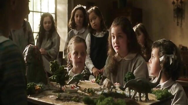 Group of cute young girls in vintage school dresses around table