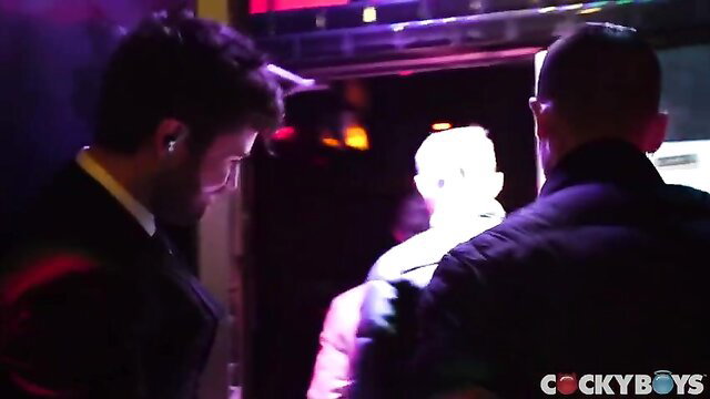 Three hot guys in suits hook up in neon-lit dungeon club