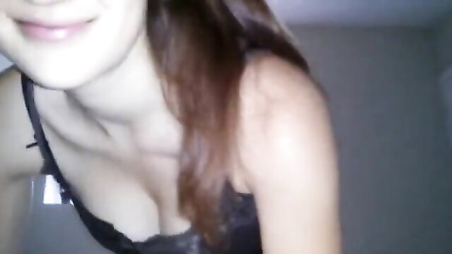 Brunette beauty in black lace bra smiles close-up, teasing cleavage