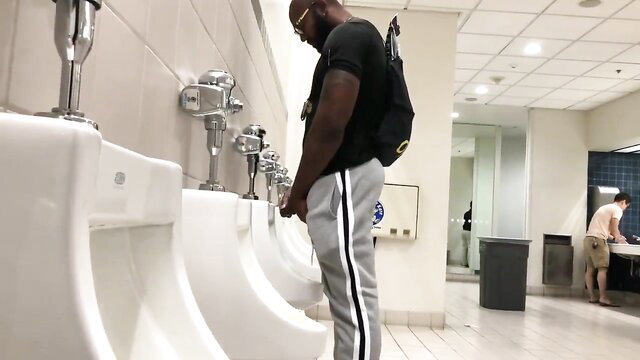 Black guy in track pants using public urinal, discreet bathroom thumbnail