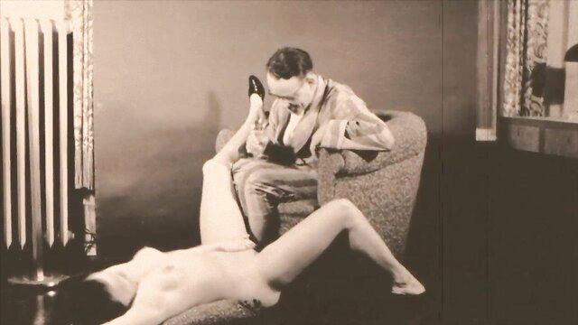 Vintage granny holds high heel on man's face, nude leg over lap
