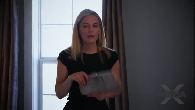 Blonde woman in black dress holding tablet in studio scene