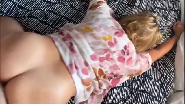 Brianna Beach bottomless on bed, wearing floral top, curvy ass and legs view