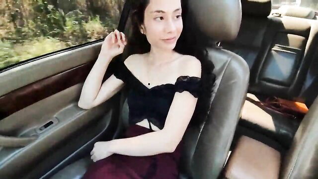 Asian beauty in off-shoulder black lace top and maroon skirt in car