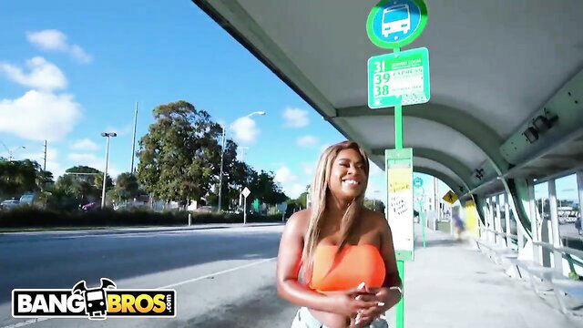 Busty black babe in orange top and daisy dukes at bus stop, big butt tease