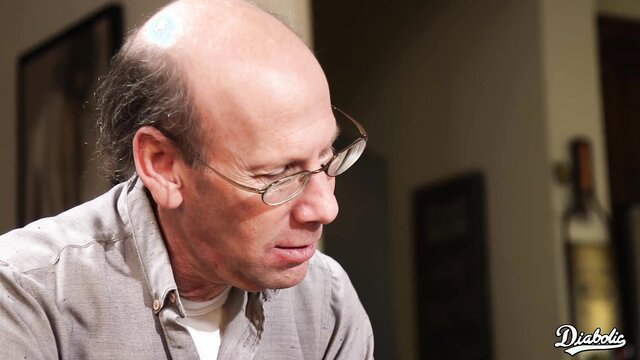 Bald mature man with glasses in dim light, closeup portrait
