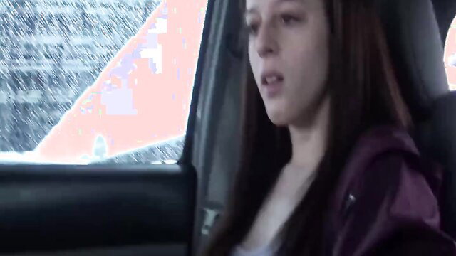 Young brunette babe in car, sexy hooded top, intense gaze