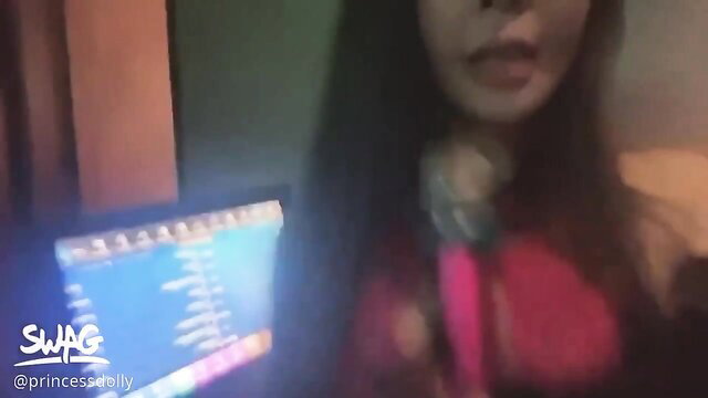 Asian girl with long black hair sings into pink mic in tight red top at KTV