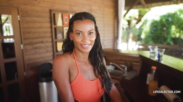 Smiling mixed-race Lya Cutie in orange halter top at tropical bar