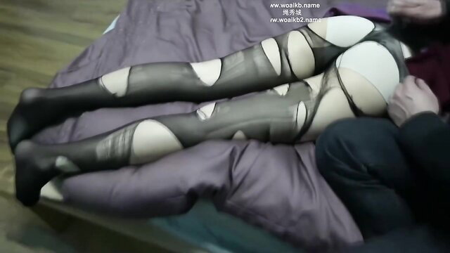 Asian girl in torn black stockings BDSM pose on bed