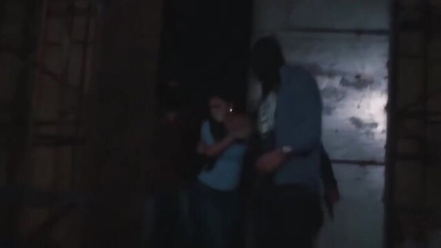 Blonde teen held by masked man in dark BDSM scene