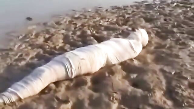 Woman fully wrapped in white bandages buried in mud BDSM fetish
