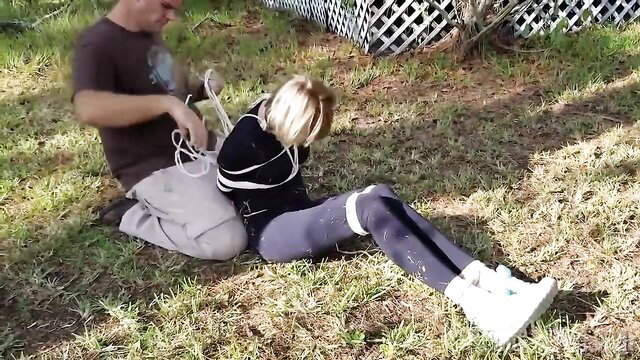 Blonde jogger bound with white rope outdoors, kidnapped fetish BDSM scene