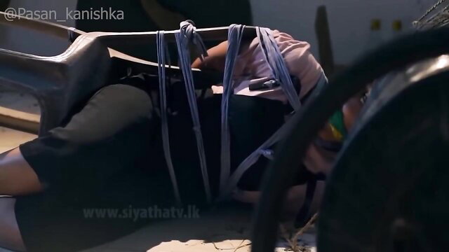 Asian woman bound with ropes in BDSM scene, tied on chair