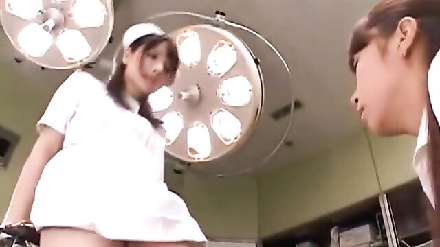 Two cute Japanese nurses in short uniforms under hospital lights BDSM scene