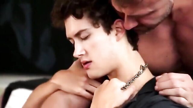 Muscular daddy gropes curly-haired twink boy's neck with chain collar