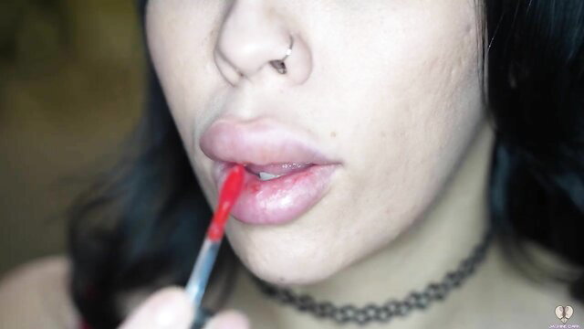 Jasmine Dark applying red lipstick with bimbo plump lips closeup