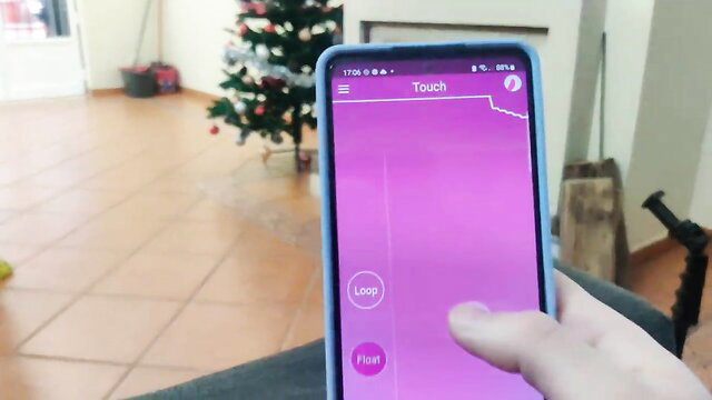 Hand touching pink screen on phone near Christmas tree in maid video thumbnail