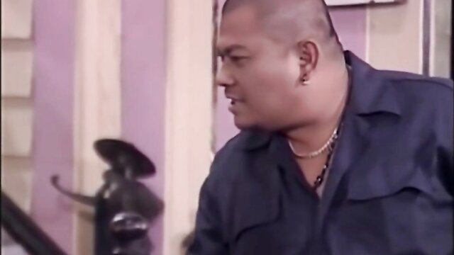 Bald muscular Latino man in BDSM scene with women on couch