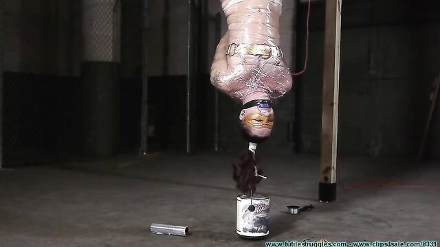 Woman mummified in saran wrap, bound and hung upside down in BDSM suspension