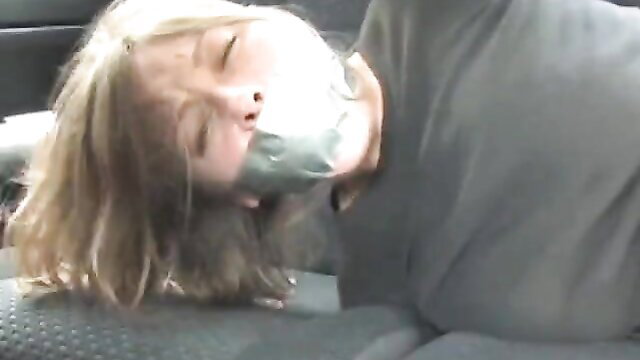 Blonde girl bound and tape gagged in car kidnapping fetish scene