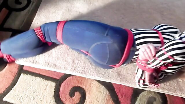 Blonde in Spider-Man cosplay bound tight in tight jeans BDSM pose