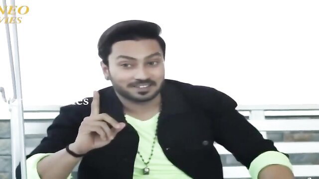 Indian man in green shirt black blazer gesturing excitedly