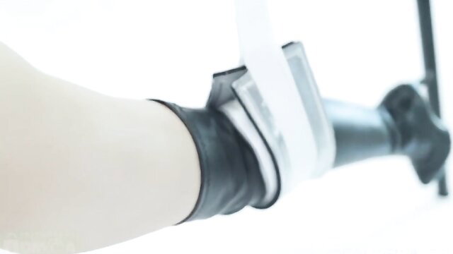 BDSM bound leg in black leather cuffs and stockings, sexy restraint tease