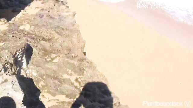 Couple risks outdoor sex on rocky beach cliff by ocean waves