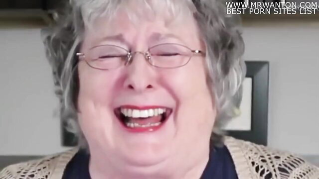 Smiling mature granny with glasses laughs in sexy crochet top