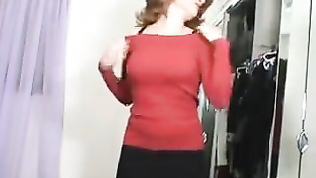 Redhead in tight red top and black skirt posing sexy in closet mirror