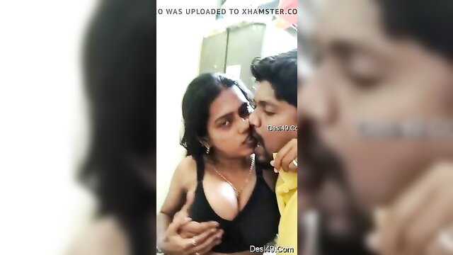 Indian couple kissing passionately, her deep cleavage in black tank top