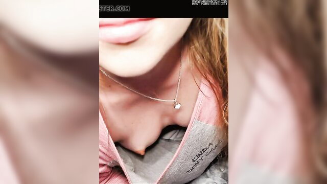 Closeup of busty redhead's cleavage in pink top, necklace tease