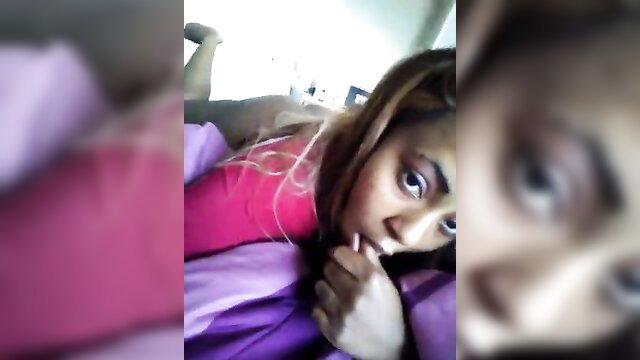 Blurry close-up of seductive black woman in pink top biting lip on bed