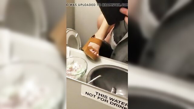 Blurry closeup of woman's tan legs and high heels near toilet sink
