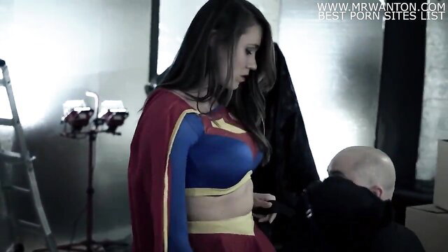 Supergirl in superhero costume kneels for action with bald man