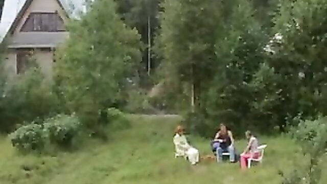 Three amateur family women in dresses sitting outdoors on chairs
