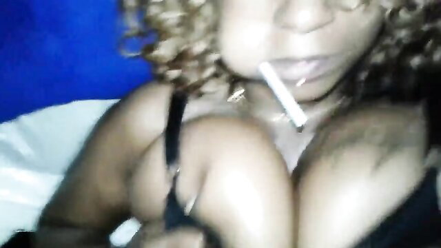 Curvy black woman in bra smoking cigarette, teasing cleavage