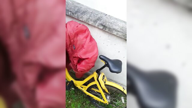 Red backpack covering yellow bike seat outdoors, casual thumbnail