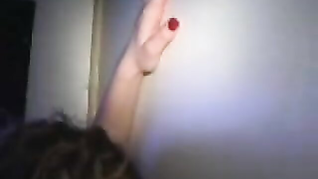 Closeup of woman's hand with red nail polish at glory hole