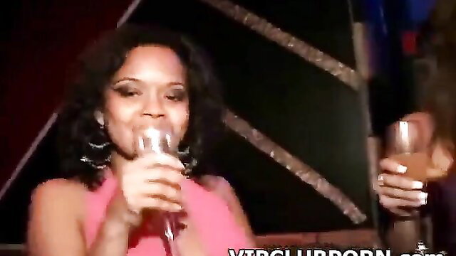 Black woman in pink dress sings with mic at kinky VIP club party