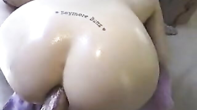 Shiny latex ass tattooed 'Seymore Butts' bent over closeup
