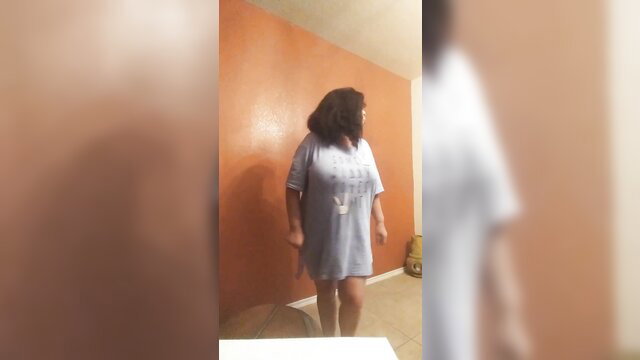 Latina BBW in tight t-shirt stands teasingly, big tits highlighted