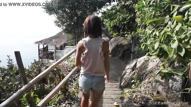 Asian teen in tiny denim shorts walks on tropical path, big ass tease