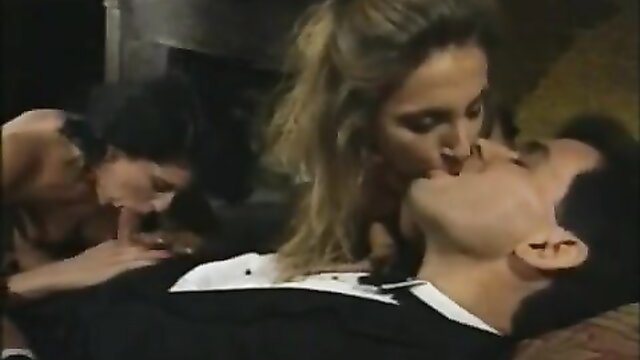 Blonde and brunette women kissing suited man in steamy threesome scene