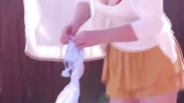 Japanese mom in white top and yellow skirt holds blue panties at home