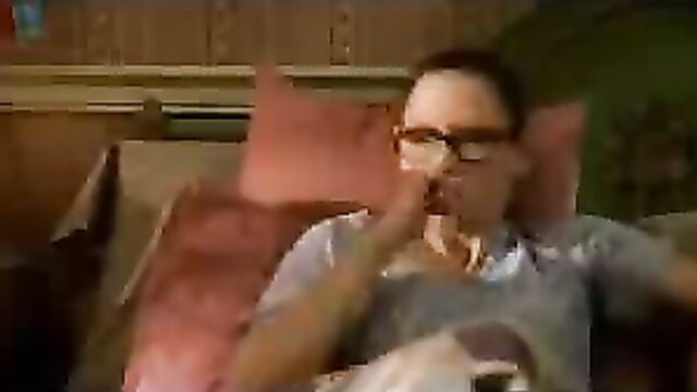 Brunette in glasses smokes on couch in sexy gray top, amateur tease