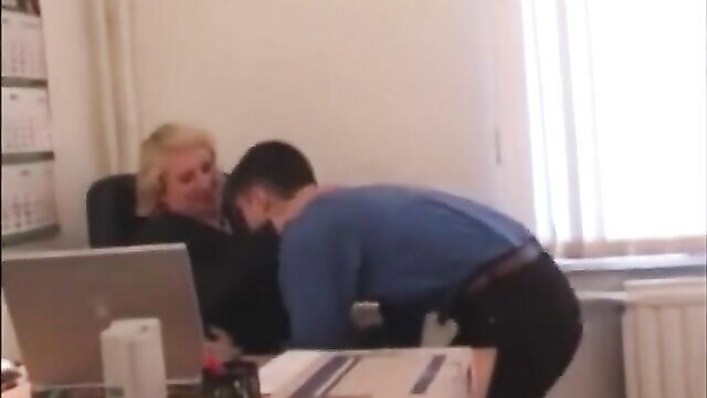 Blonde mature Russian woman at desk with young man kneeling behind her