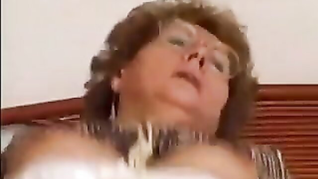 Closeup of busty mature granny with glasses in bed, explicit oral scene