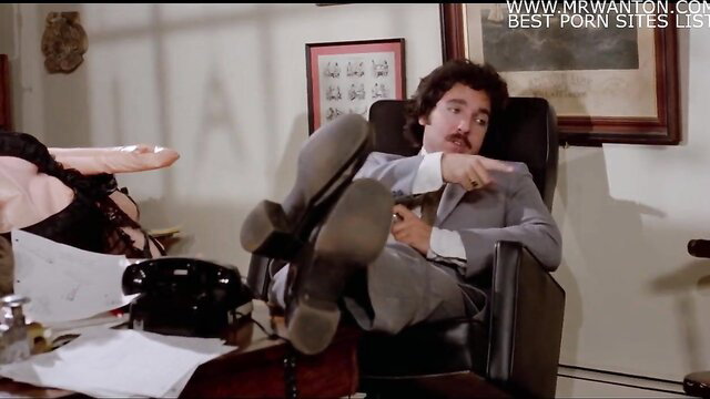 Curly haired man in suit points at nude woman footjob in office